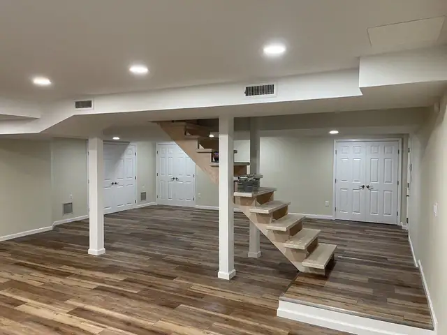 Finished basement with wide-plank flooring, recessed lights, white posts and open stairs